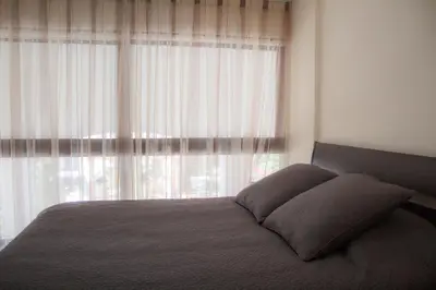 a bedroom with a bed with a large window at Galatex Beach Apartment in Limassol