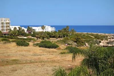 a view of a beach with a building and the ocean at Apartment Victoria in Protaras