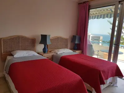two beds in a bedroom with a view of the ocean at Alania Sea View Apartment in Limassol