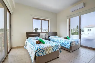 a bedroom with two beds and a balcony at Villa Eva in Ayia Napa