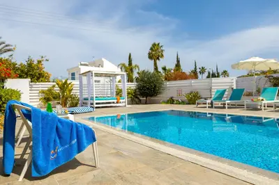a swimming pool with chairs and a blue towel on it at Fig Tree Bay Villa 3 in Protaras