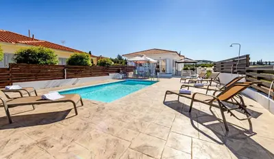 a swimming pool with lounge chairs next to a house at Sunset Villa Protaras in Protaras