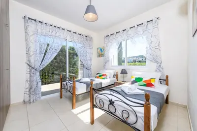 a bedroom with two beds and a window at Sunset Villa Protaras in Protaras