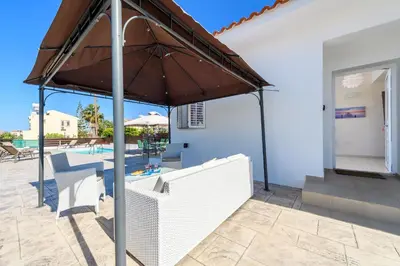 a patio with an umbrella and a pool at Sunset Villa Protaras in Protaras