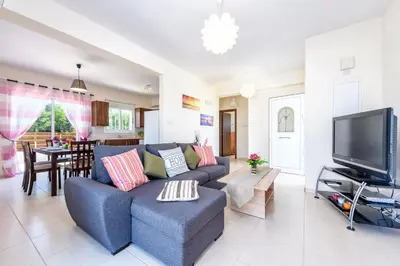 a living room with a blue couch and a tv at Sunset Villa Protaras in Protaras