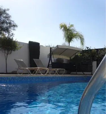 a swimming pool with chairs and a table and a umbrella at Cy-Blue in Protaras