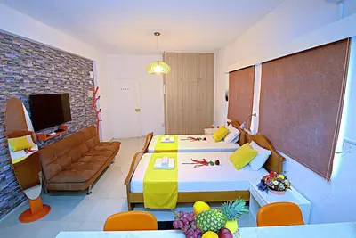 a bedroom with two beds and a living room at Pieris Apartments in Ayia Napa