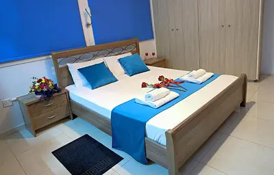 a bedroom with a large bed with blue walls at Pieris Apartments in Ayia Napa