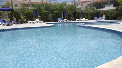 a large swimming pool with chairs and umbrellas at Pyla Gardens A101 in Pyla