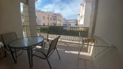 a glass table and chairs on a balcony with a view at Pyla Gardens A101 in Pyla