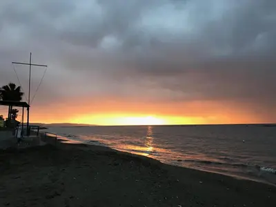 a sunset on a beach with the ocean at Athena Holiday Homes in Limassol