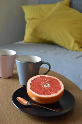 a grapefruit on a plate next to a cup of coffee at Athena Holiday Homes in Limassol