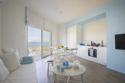 a living room with a table and a kitchen with a view at Azure Beachfront Suite in Protaras