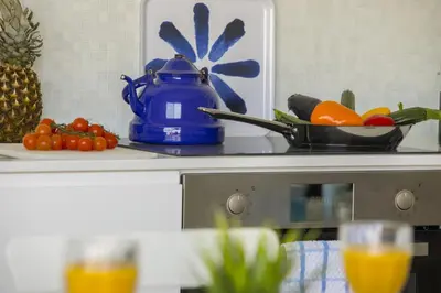 a kitchen counter with a blue tea pot and fruit at Azure Beachfront Suite in Protaras