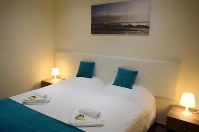 two beds in a room with two lamps and a painting at Cross Road in Ayia Napa