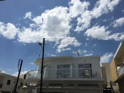 a white house with a balcony on a street at Cross Road in Ayia Napa