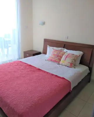 a bed with pink and white sheets and pillows at T&E Apartment in Larnaka