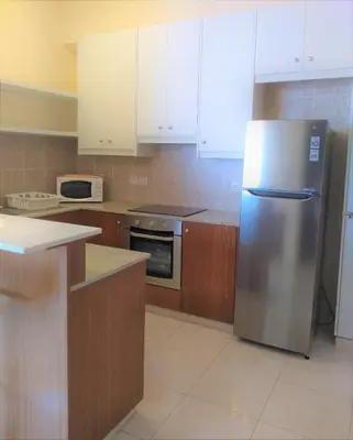 a kitchen with a stainless steel refrigerator and wooden cabinets at T&E Apartment in Larnaka