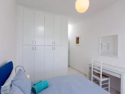 a white bedroom with a bed and a ladder at On The Beach Penthouse by TrulyCyprus in Limassol