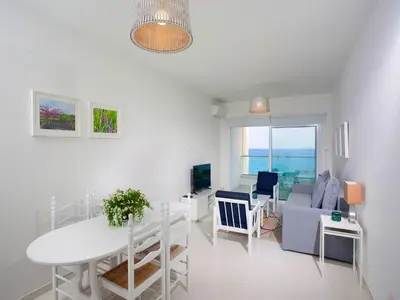 a white living room with a table and a couch at On The Beach Penthouse by TrulyCyprus in Limassol