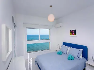 a bedroom with a bed and a window with the ocean at On The Beach Penthouse by TrulyCyprus in Limassol