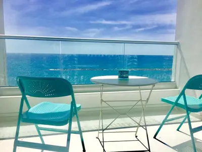 a table and chairs in a room with a window at On The Beach Penthouse by TrulyCyprus in Limassol
