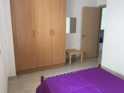 a bedroom with a purple bed and wooden cabinets at Great Kings Resort Apartment 10 Block 19 in Protaras