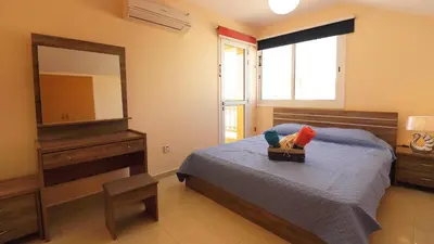 a bedroom with a bed with a dresser and a mirror at Panikos Beach Apartment I in Larnaka