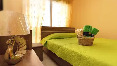 a bedroom with a bed with a lamp and green sheets at Panikos Beach Apartment I in Larnaka