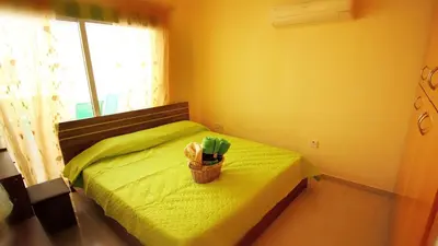 a bedroom with a green bed with a basket on it at Panikos Beach Apartment I in Larnaka