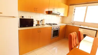 a kitchen with orange cabinets and a stove top oven at Panikos Beach Apartment I in Larnaka