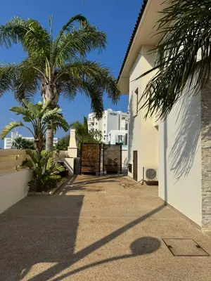 a driveway with palm trees and a white building at Villa Sotmarie in Protaras