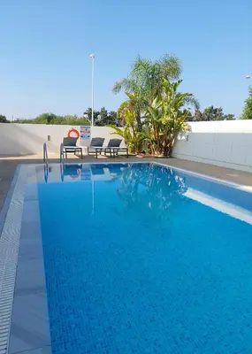 a swimming pool with two chairs next to a building at Villa Sotmarie in Protaras