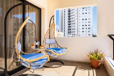 a balcony with two hanging chairs and a table at CityDen in Larnaka