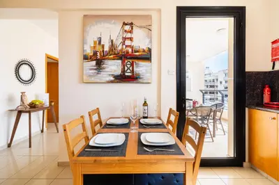 a dining room table with chairs and a painting on the wall at CityDen in Larnaka
