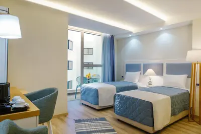 a hotel room with two beds and a table at Qbic City Hotel in Larnaka