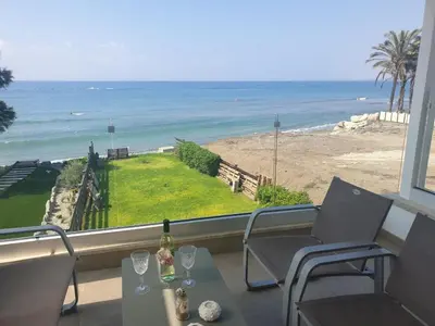 a balcony with a table and chairs and the ocean at Periyiali Beach Sunset Suite A7 in Pervolia