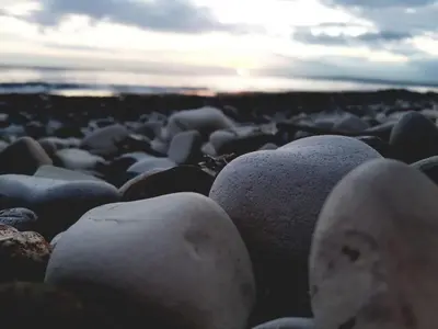 a group of rocks on a beach with the sunset at Periyiali Beach Sunset Suite A7 in Pervolia