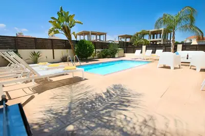 a swimming pool with white chairs and a swimming pool at Casa Di Kappari in Protaras