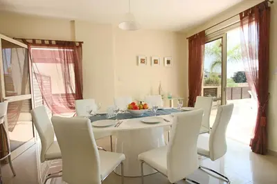 a white dining room with a table and chairs at Casa Di Kappari in Protaras
