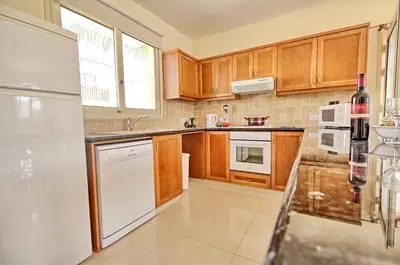 a kitchen with wooden cabinets and a white refrigerator at Casa Di Kappari in Protaras