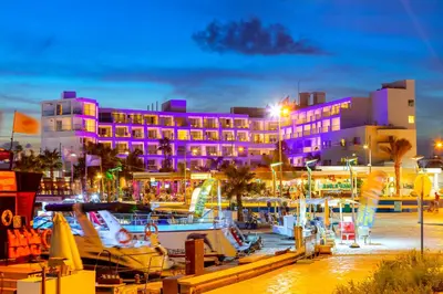 a hotel with purple lights in a marina at night at Limanaki Beach Hotel & Suites in Ayia Napa