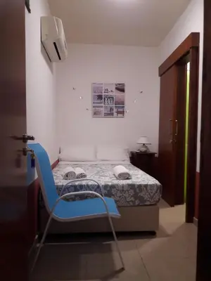 a blue chair in a room with a bed at Marina's Rooms in Larnaka