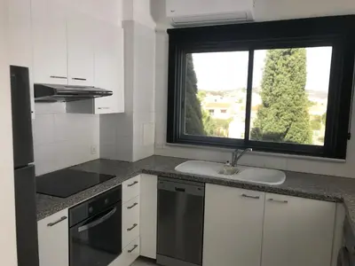 a white kitchen with a sink and a window at Olosuites in Limassol
