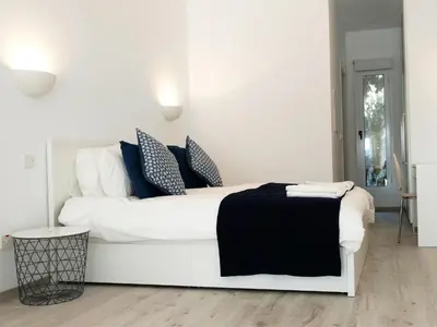 a white bed with blue pillows in a white room at Olosuites in Limassol