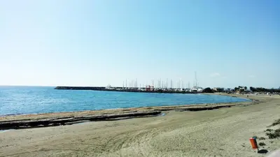 a sandy beach with a pier in the water at Olosuites in Limassol