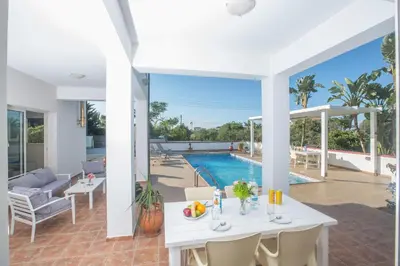 a patio with a white table and chairs and a pool at Villa Orka in Protaras