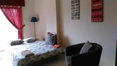 a bedroom with a bed and a chair and a window at Modern City Center Apt in Larnaka