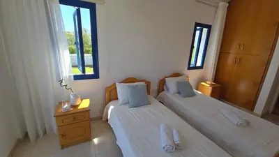 two beds in a room with two windows at Villa Jenny in Protaras