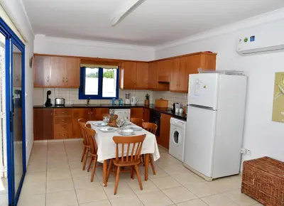 a kitchen with a table and chairs and a white refrigerator at Villa Jenny in Protaras